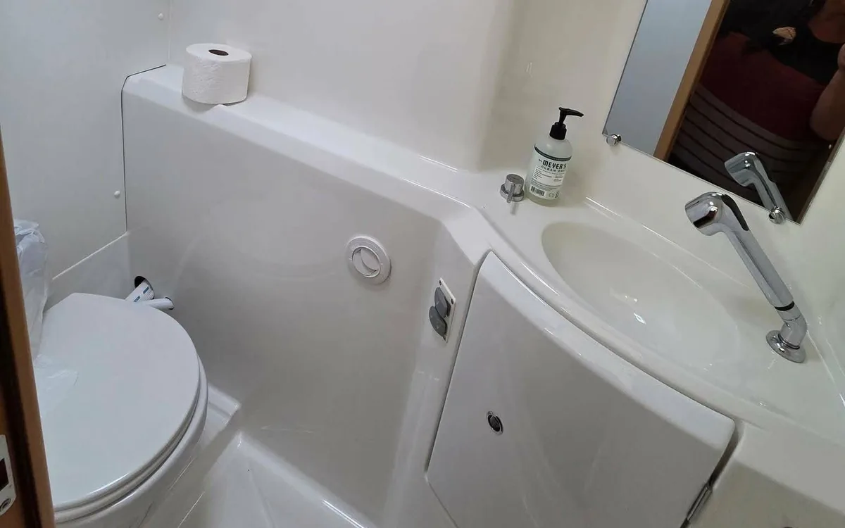 Majik’s head: a clean white marine bathroom with sink, counter and toilet